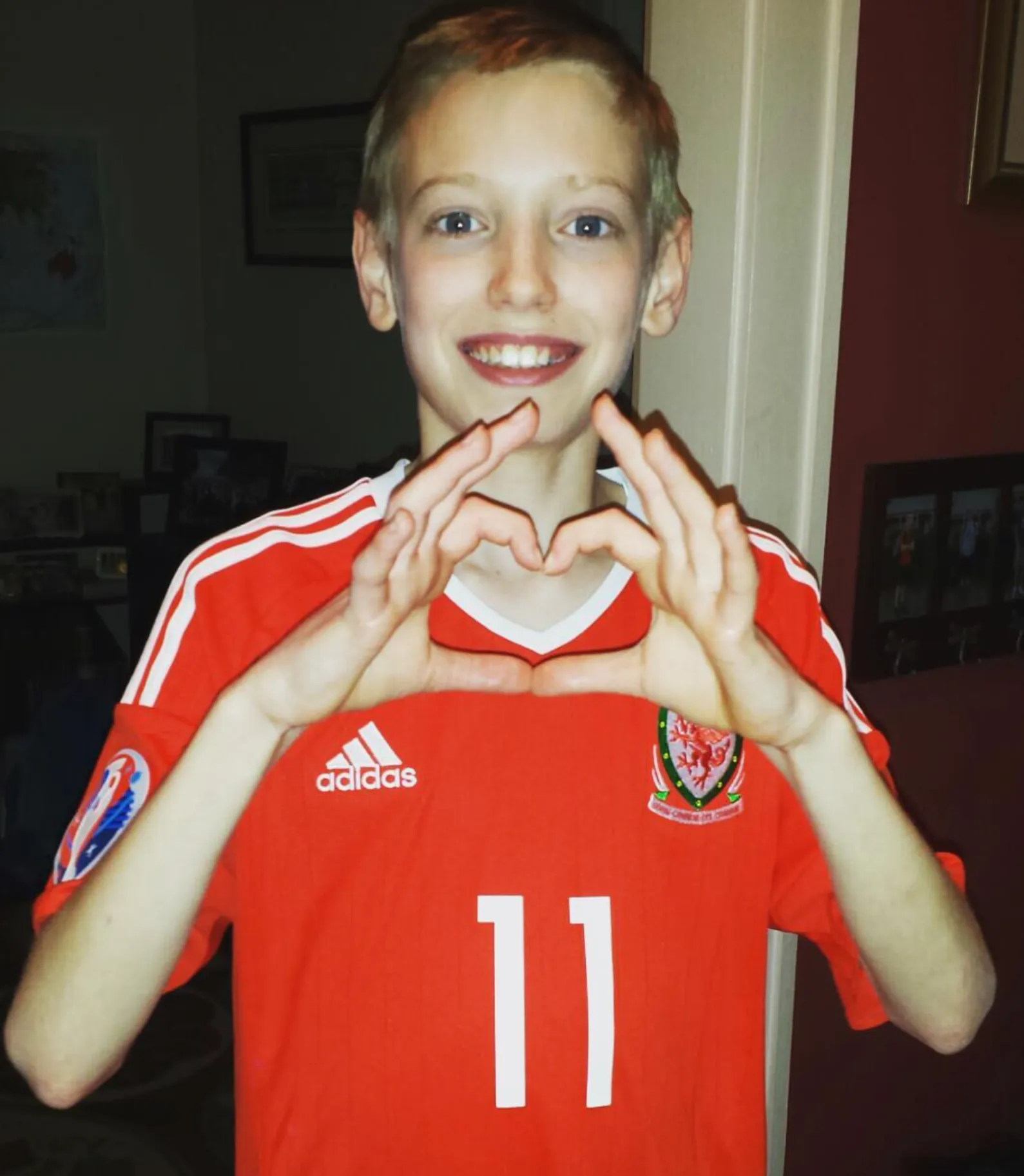 Reece in a Wales jersey making a heart shape with his hands